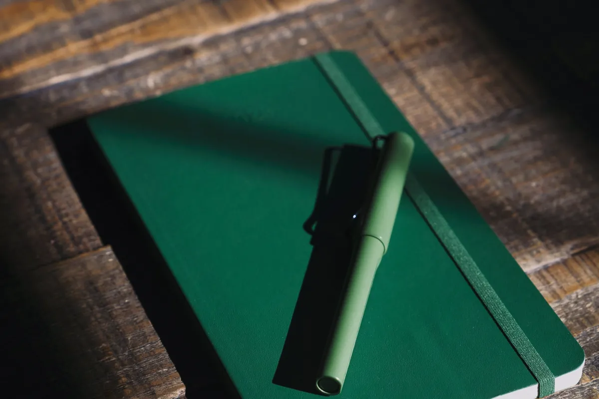 Carnet vert et stylo sur une table de bois