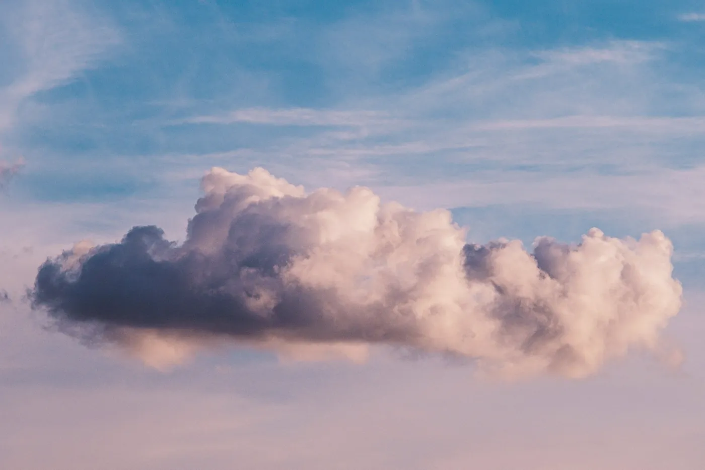 Un nuage isolé, rosé, dans un ciel bleu